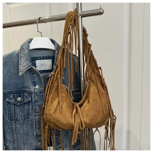 Primer plano del bolso hobo de gamuza color caramelo con flecos largos en una percha
