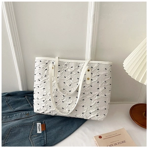 Détail du sac cabas blanc avec tissu plissé 3D et motifs de nœuds noirs élégants
