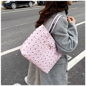 Détail du sac fourre-tout rose avec imprimé nœuds noirs et breloque dorée en métal