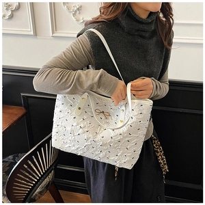 Détail du sac cabas blanc avec broderie de nœuds noirs et pendentif doré