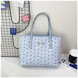 Détail du sac cabas bleu clair avec texture plissée et décoration nœud doré