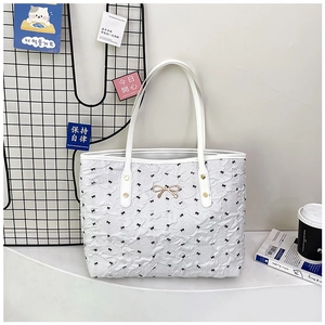 Détail du sac cabas blanc en tissu gaufré avec motifs de nœuds papillon noirs