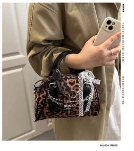 Detail of leopard print handbag with silver chain, cross pendant and lace bow accents