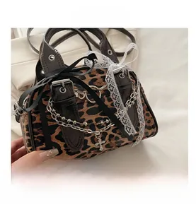 Detail of leopard print handbag with cross pendant, metal chains and decorative bows