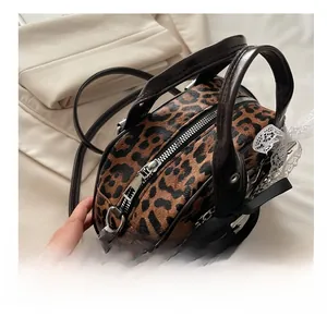 Detail view of smooth metal zipper and leopard print texture on a barrel handbag