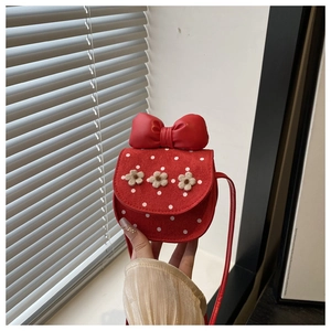 Detail of red suede crossbody bag for girls featuring fuzzy flowers and a large bow knot