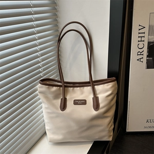 Minimalist beige canvas tote bag with brown leather handles for daily commute style