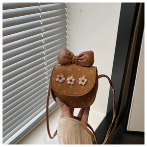 Detail of suede kids crossbody bag with leather bow, pink polka dots and floral accents