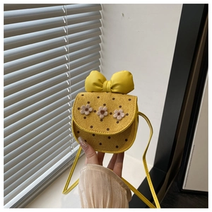 Close-up of yellow children's crossbody bag with polka dots and floral bow detail