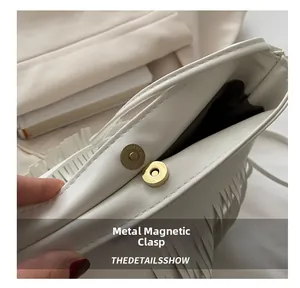 Détail du fermoir magnétique doré sur un sac à main blanc en similicuir à franges
