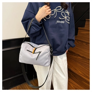 Close-up of lightweight nylon crossbody bag with front zipper pocket and orange pull tab detail