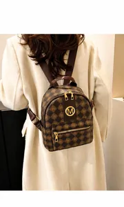 Detail of a brown leather backpack featuring embossed letter patterns and gold hardware