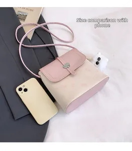 Size comparison of a mini printed crossbody bag next to a smartphone and accessories