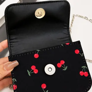Détail du fermoir magnétique sur sac carré à imprimé cerise avec bandoulière chaîne