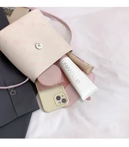 Interior storage of pink cartoon kitty crossbody bag showing phone and cosmetics