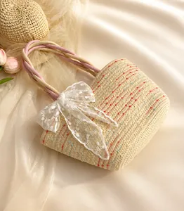 Detalle del bolso de paja beige con lunares de colores y gran lazo de encaje blanco