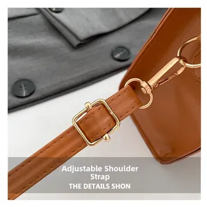 Close-up of adjustable shoulder strap with gold metal buckle on brown leather bag