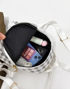 Interior storage view of a white letter print backpack holding a phone and daily essentials