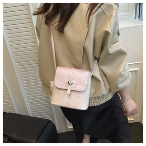 Close-up of pink bucket bag with heart buckle, bear print, and white fur ball charm