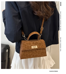Detail of a brown leopard print crossbody bag with a gold twist lock and a top handle