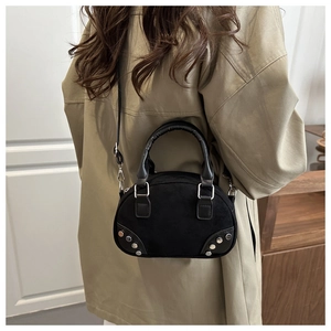 Detail of black suede shoulder bag with silver studs and pleated handle on a model