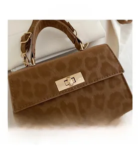 Detail of brown leopard patterned handbag with a gold-tone metallic twist lock closure