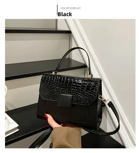 Close-up of black crossbody bag with faux crocodile flap and golden metal clasp