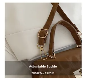 Detail of golden metal buckle and adjustable brown leather strap on commute crossbody bag