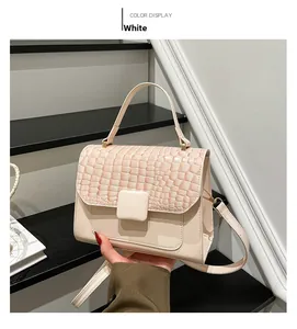 Detail of off-white crossbody bag with crocodile embossed flap and square buckle strap