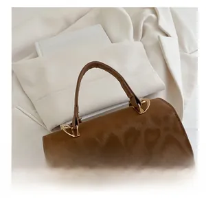 Close-up of leopard print suede handbag with elegant golden twist lock and metal handle