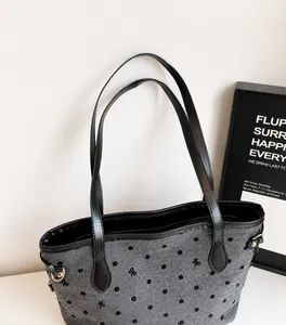 Détail du sac cabas gris à pois avec broderie de nœud et bandoulière en cuir noir chic