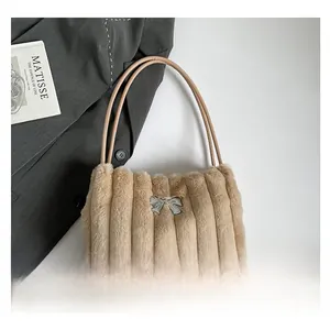 Detail of light brown faux fur bucket bag featuring vertical stripes and a silver bow
