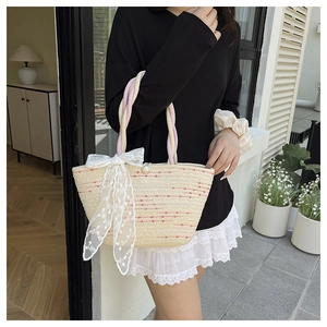 Detalle del bolso de paja tejida con lunares de colores y un gran lazo de encaje blanco