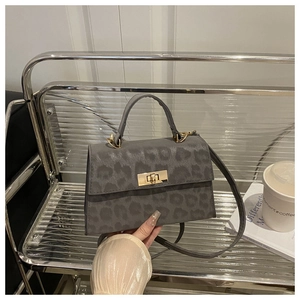 Detail of grey leopard print handbag featuring a gold-tone twist lock and top handle