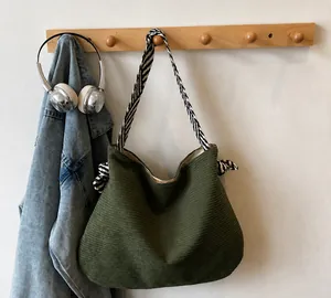 Détail du sac hobo en velours côtelé vert foncé avec bandoulière rayée sur crochet