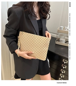Close-up of vintage patterned clutch bag with wrist strap held by model in black suit