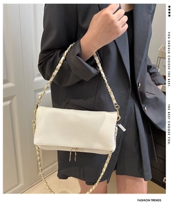 Detail of white lychee pattern crossbody bag featuring gold metal chain and dual zippers