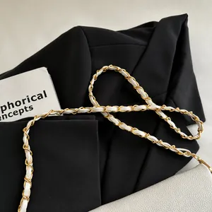 Detail of white leather interwoven with metal chain strap on litchi grain underarm bag