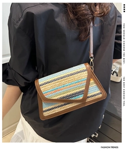 Detail of colorful striped straw crossbody bag with brown leather strap and gold buckle
