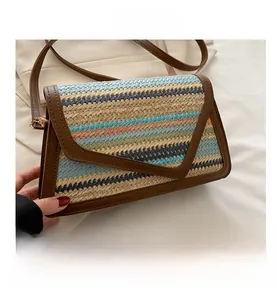 Macro detail of the woven straw bag featuring vibrant multi-color stripes and leather trim