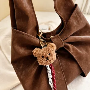 Gros plan d'un sac à main en daim marron avec un grand nœud et un ourson en peluche