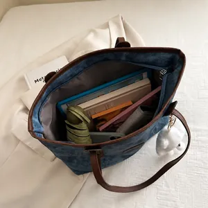 Detail showing high-capacity denim tote bag interior with tablet, books, and daily items