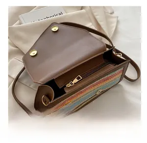 Detail view of the smooth metal zipper and magnetic closure on the straw crossbody bag