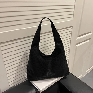 Chic black leopard print tote bag in soft suede fabric on a sofa setting