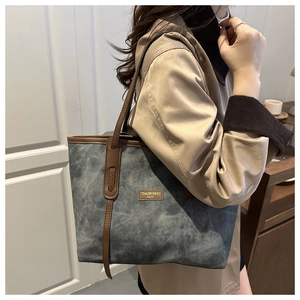 Detail der großen Shopper-Tasche aus blaugrauem Wildleder mit braunen Ledergriffen im Fokus