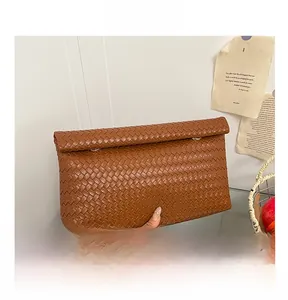 Detailed close-up of brown woven faux leather clutch with premium texture and metal ring