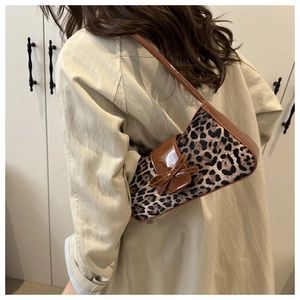 Close-up of leopard print shoulder bag with brown patent leather trim and bow detail