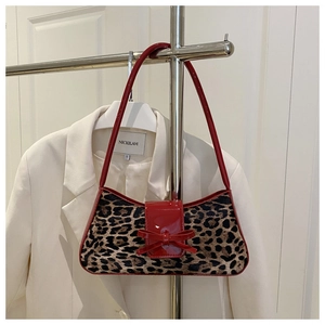 Detail of leopard print suede shoulder bag with red patent bow and slim strap design