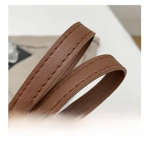Détail macro d'une bandoulière en cuir marron avec coutures de qualité et bords huilés