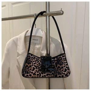 Detail of leopard print underarm bag featuring a black patent leather bow and trim